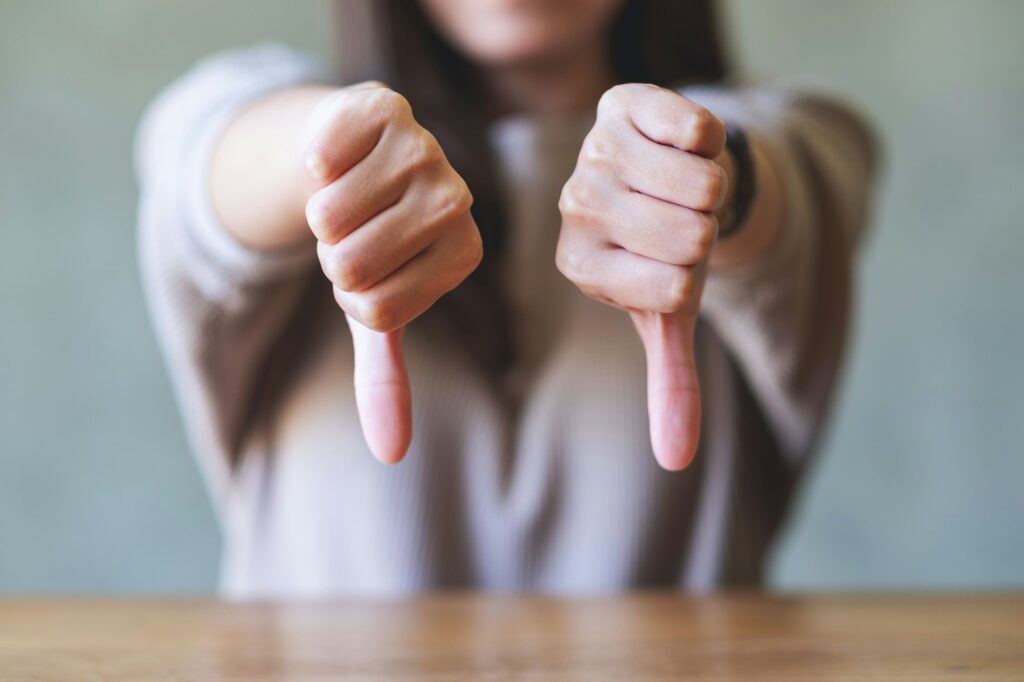Closeup image of a woman making thumbs down hands sign